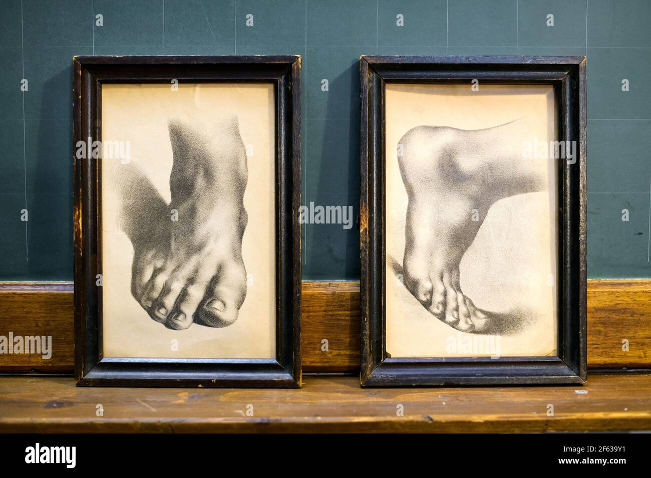 Set of two vintage drawings of human feet in different orientations in simple worn black wooden frames displayed on a shelf Stock Photo