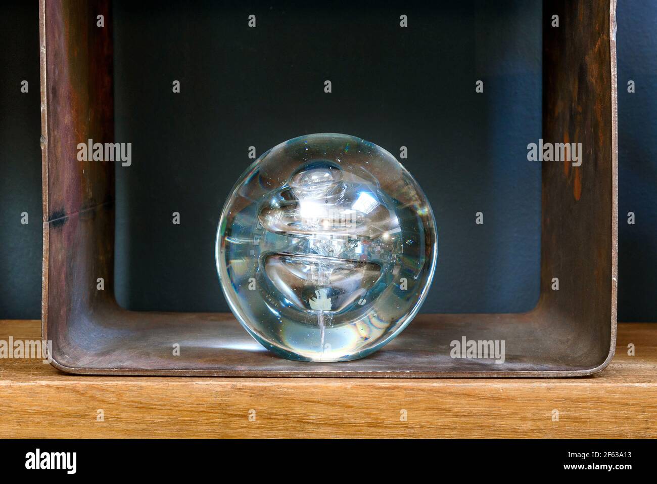 Transparent glass sphere or orb displayed on a shelf for spiritual, fortunetelling, prediction, divination or healing concepts with lateral copyspace Stock Photo