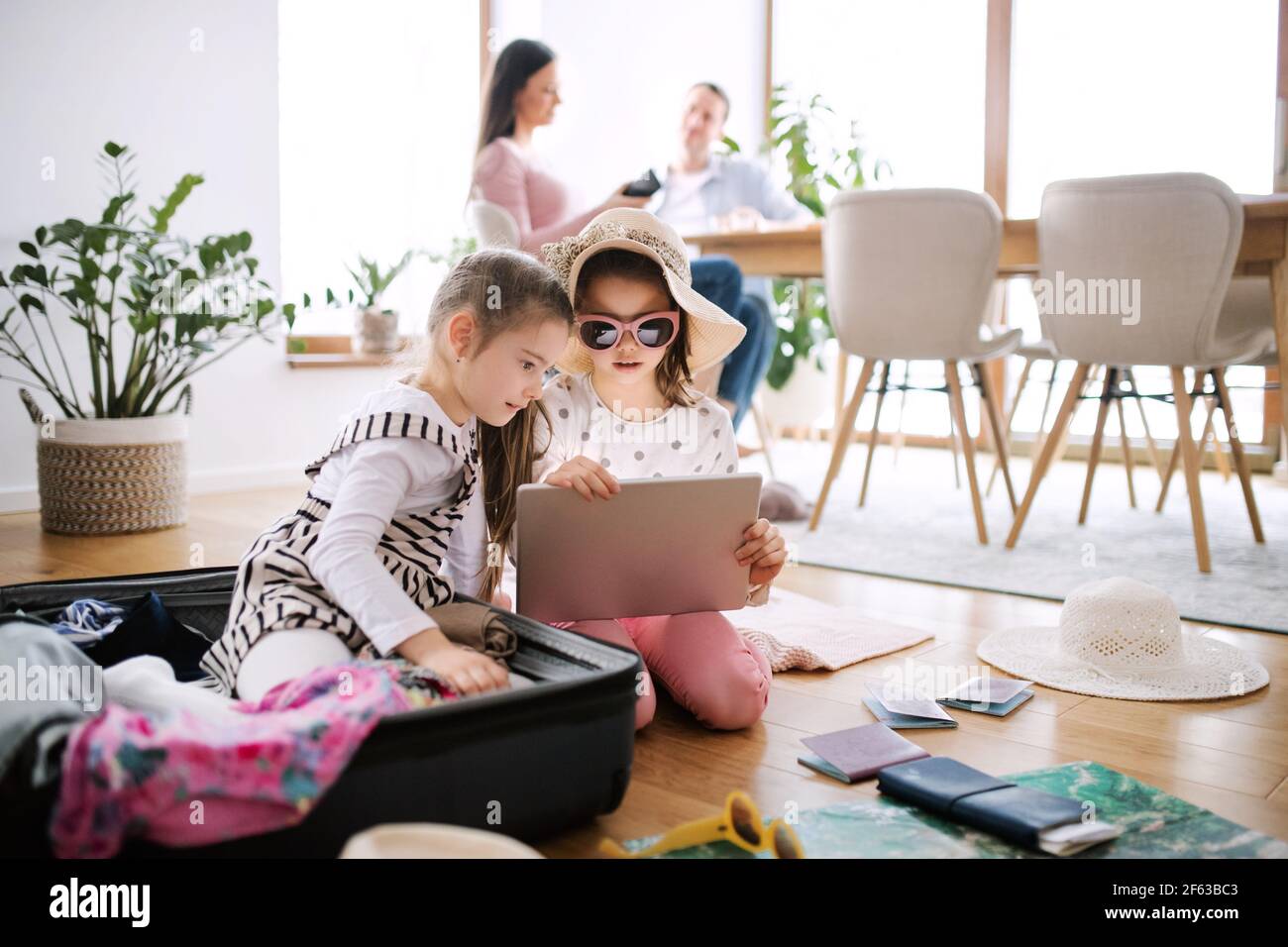 Small girls with tablet indoors at home, packing for summer holiday. Stock Photo