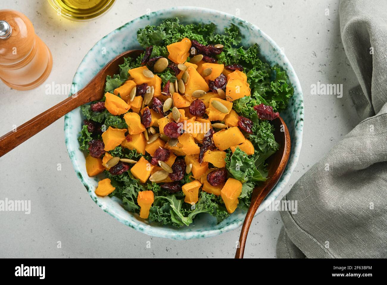 Fall salad with kale, roasted pumpkin, seeds and dried cranberries in bowl. Grey background. Mock up. Top view. Stock Photo