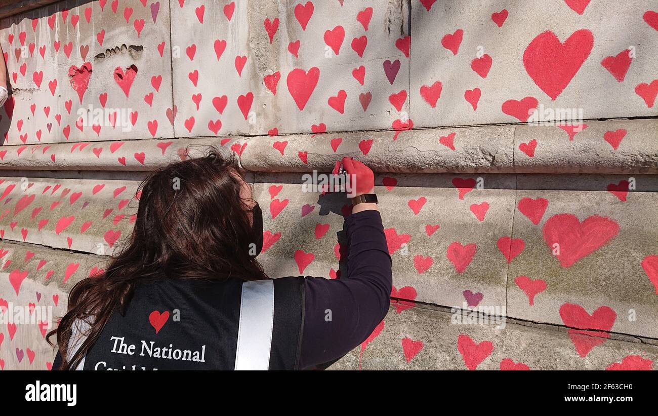 London, UK. 29th, March, 2021. Bereaved family and friends are visited by Keir Starmer as they paint hearts onto the Covid Memorial Wall. Stock Photo