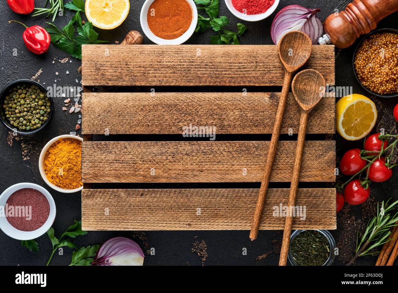 Set of Indian fragrant spices and herbs on a black stone background. Turmeric, dill, paprika, cinnamon, saffron, basil and rosemary in a spoon. Top vi Stock Photo