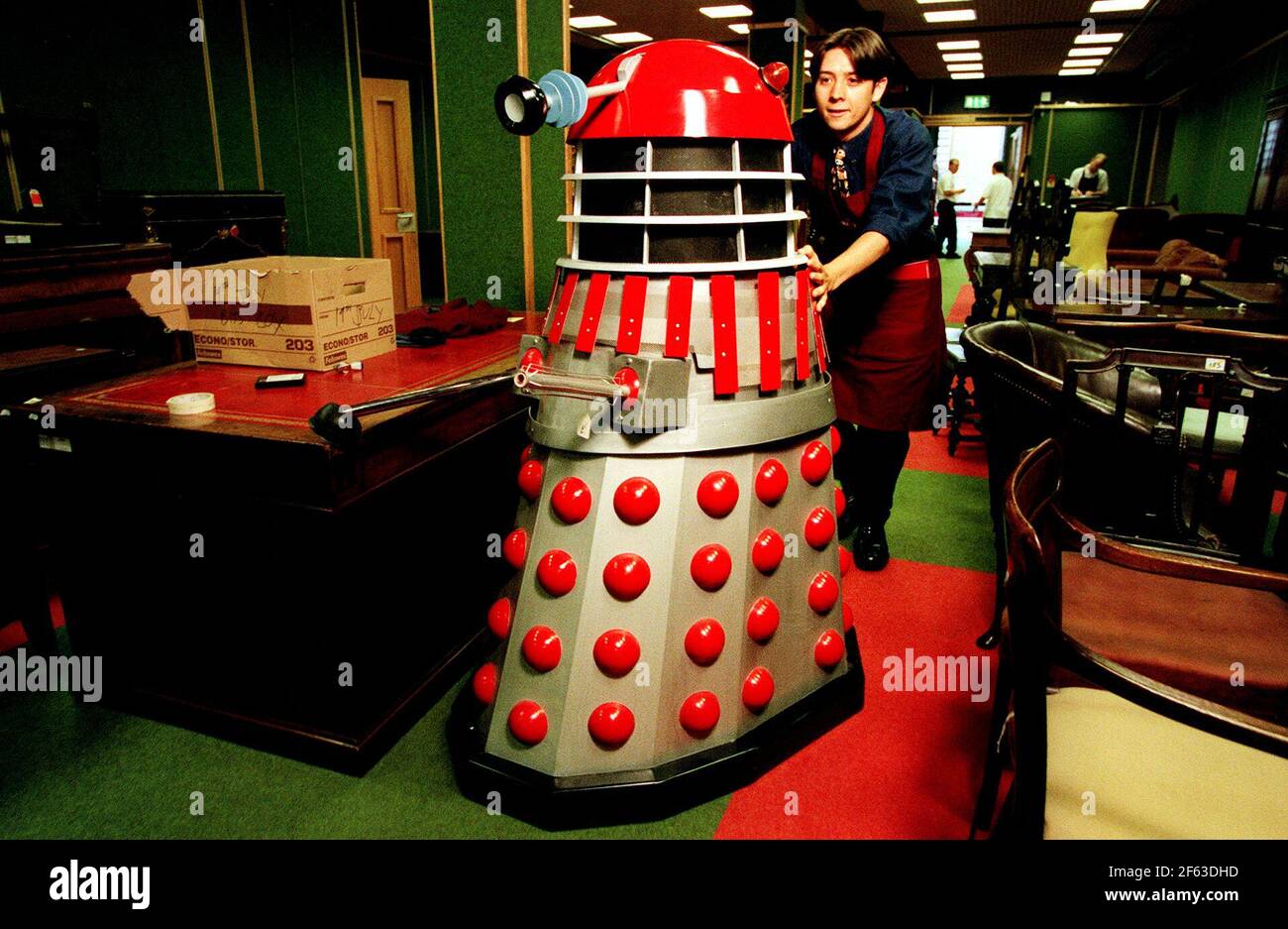 A REPLICA RED AND SILVER DALEK BEING HELPED ALONG THE CORRIDORS OF CHRISTIE'S BY PAUL GOLDER. PART OF THE TV GENERATION SALE, IS EXPECTED TO RAISE  ¿500-¿800. Stock Photo