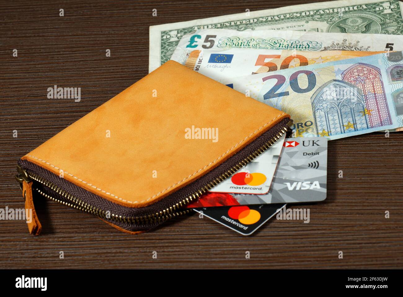 London, United Kingdom - March 15, 2021: Stack of international currencies banknotes and credit and debit bank cards inside leather wallet from differ Stock Photo