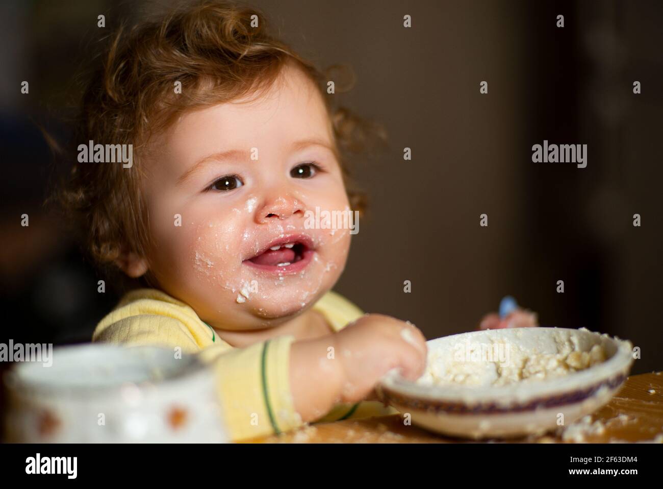 Cheerful smiling child child eats itself with a spoon Baby eating with  dirty face. Smiling little child eating food on kitchen. Kid hungry so  parent Stock Photo - Alamy
