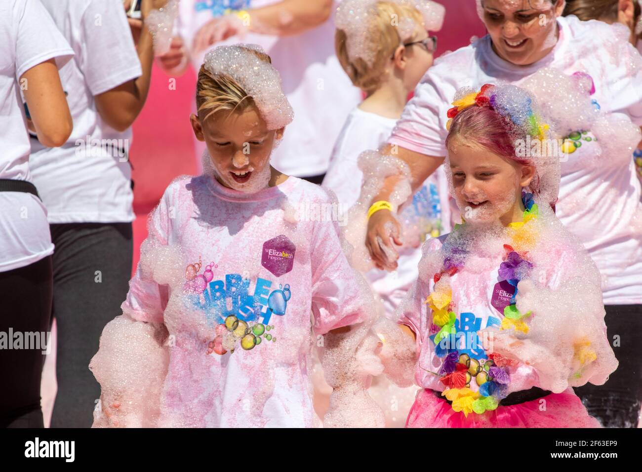Boy and girl covered in pink foam at a charity fundraiser Stock Photo