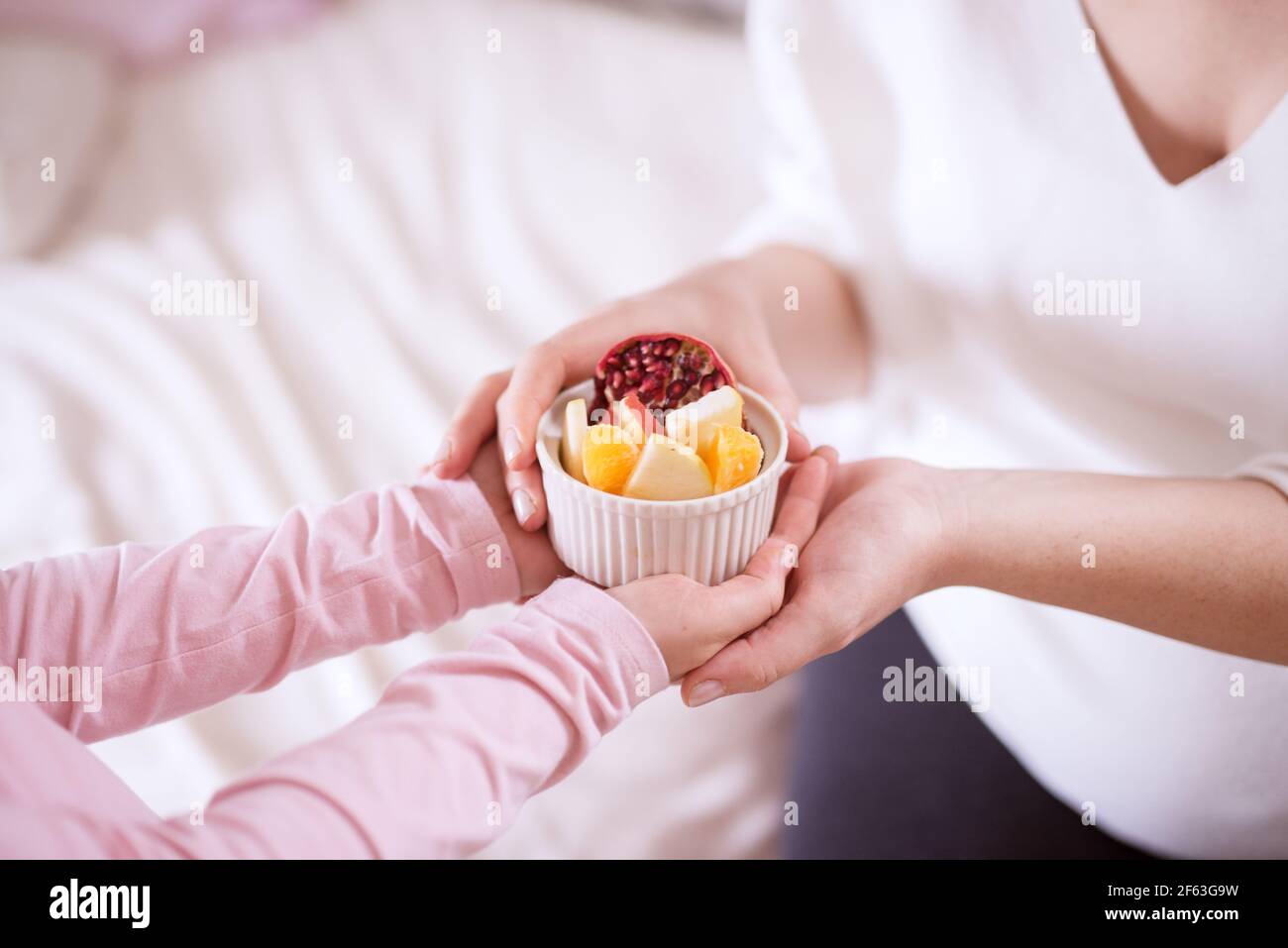 Close up of careful little toddler girl brings fruit salad to her mother. Stock Photo