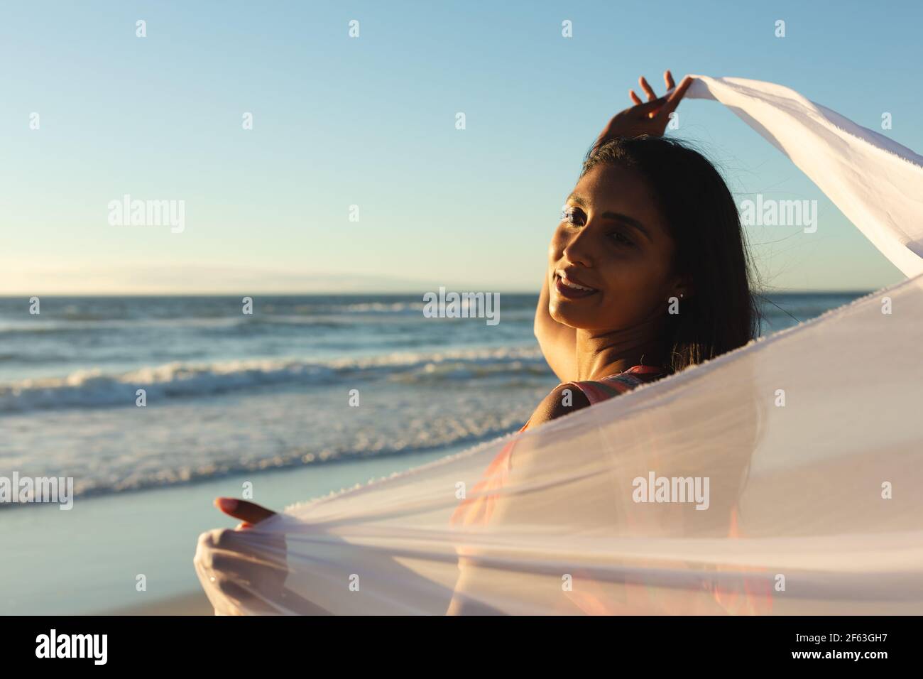 Mixed race woman on the beach holding shawl Stock Photo