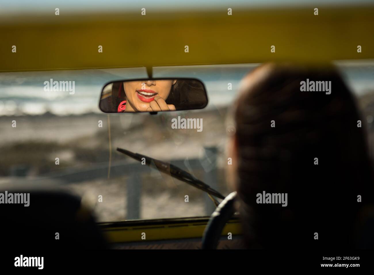 Happy caucasian woman sitting in beach buggy by the sea reflected in mirror Stock Photo