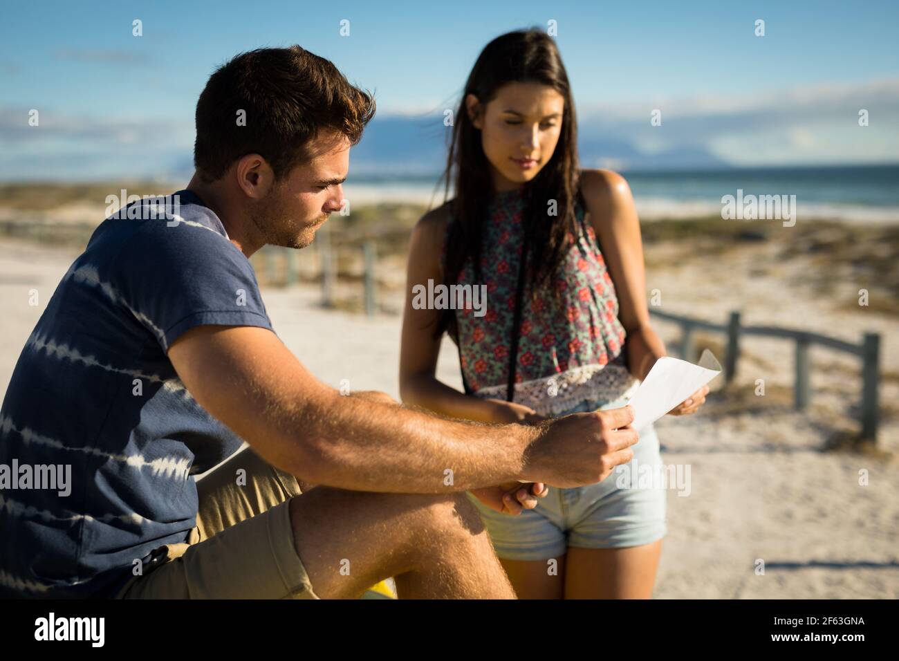 Happy caucasian couple on beach by the sea reading roadmap Stock Photo