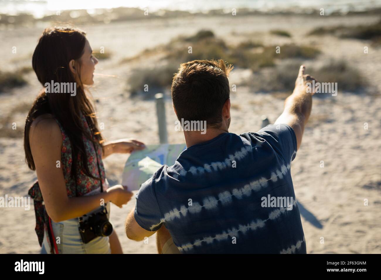 Happy caucasian couple on beach by the sea reading roadmap pointing Stock Photo