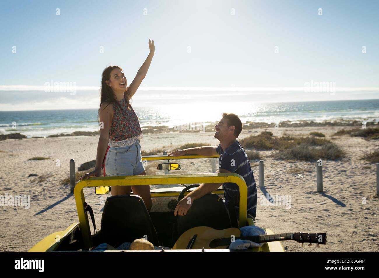 Happy caucasian couple in beach buggy by the sea smiling Stock Photo