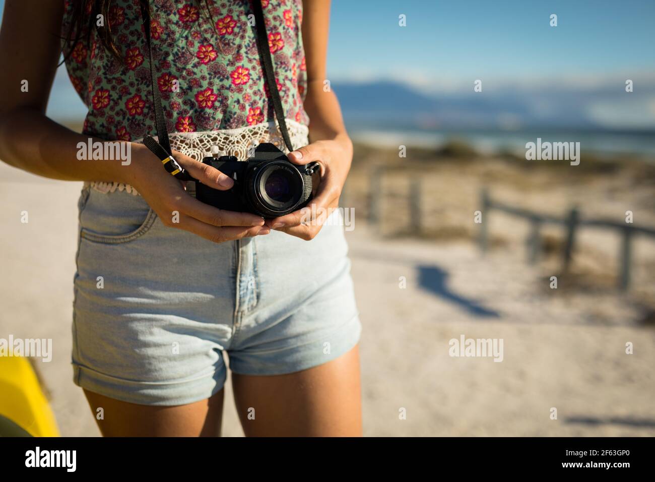 Midsection of caucasian woman on beach by the sea holding camera Stock Photo