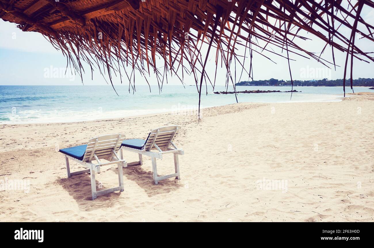 Sunbeds on a tropical beach, color toned picture. Stock Photo