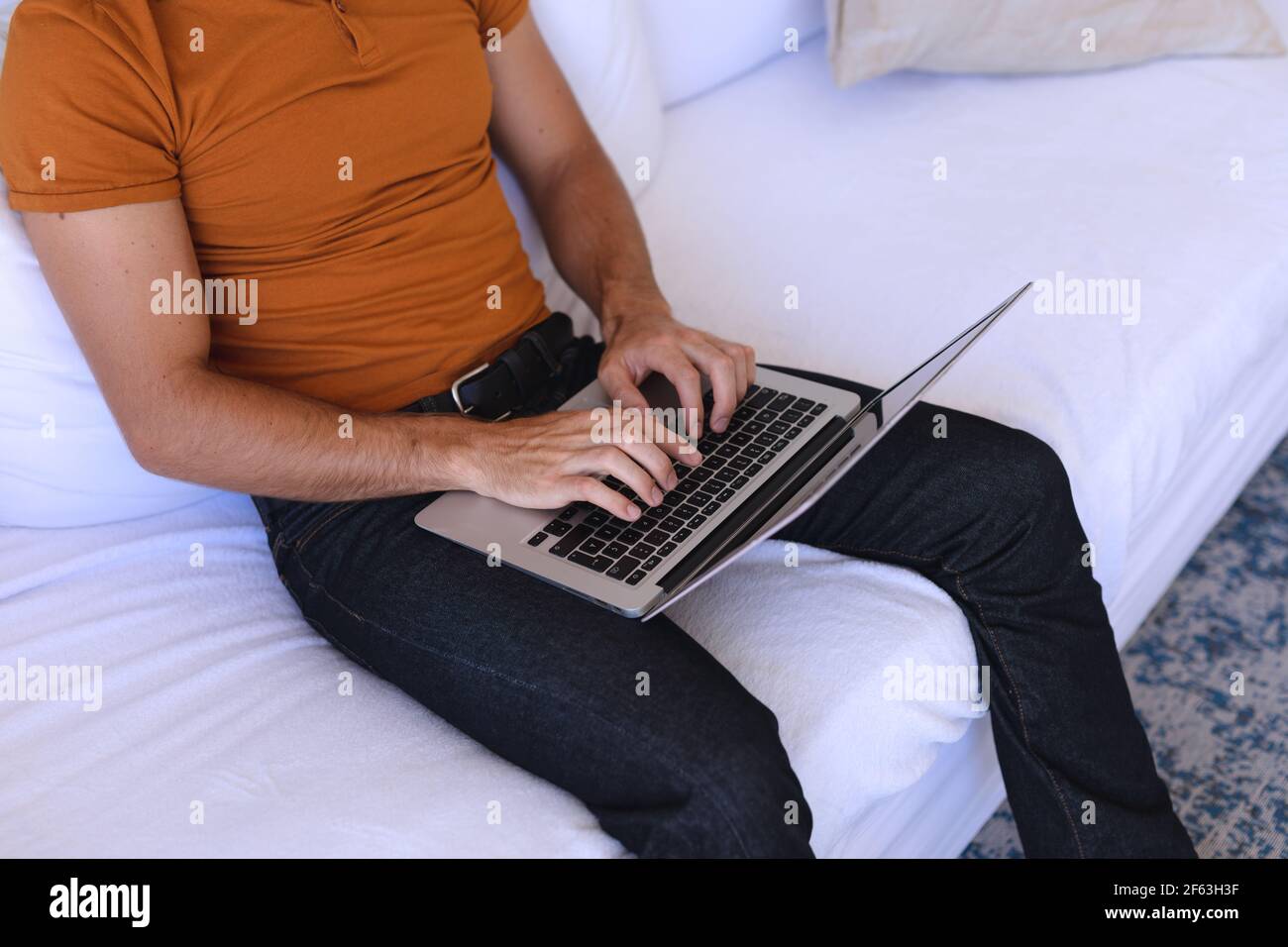 Caucasian man sitting on sofa using laptop Stock Photo