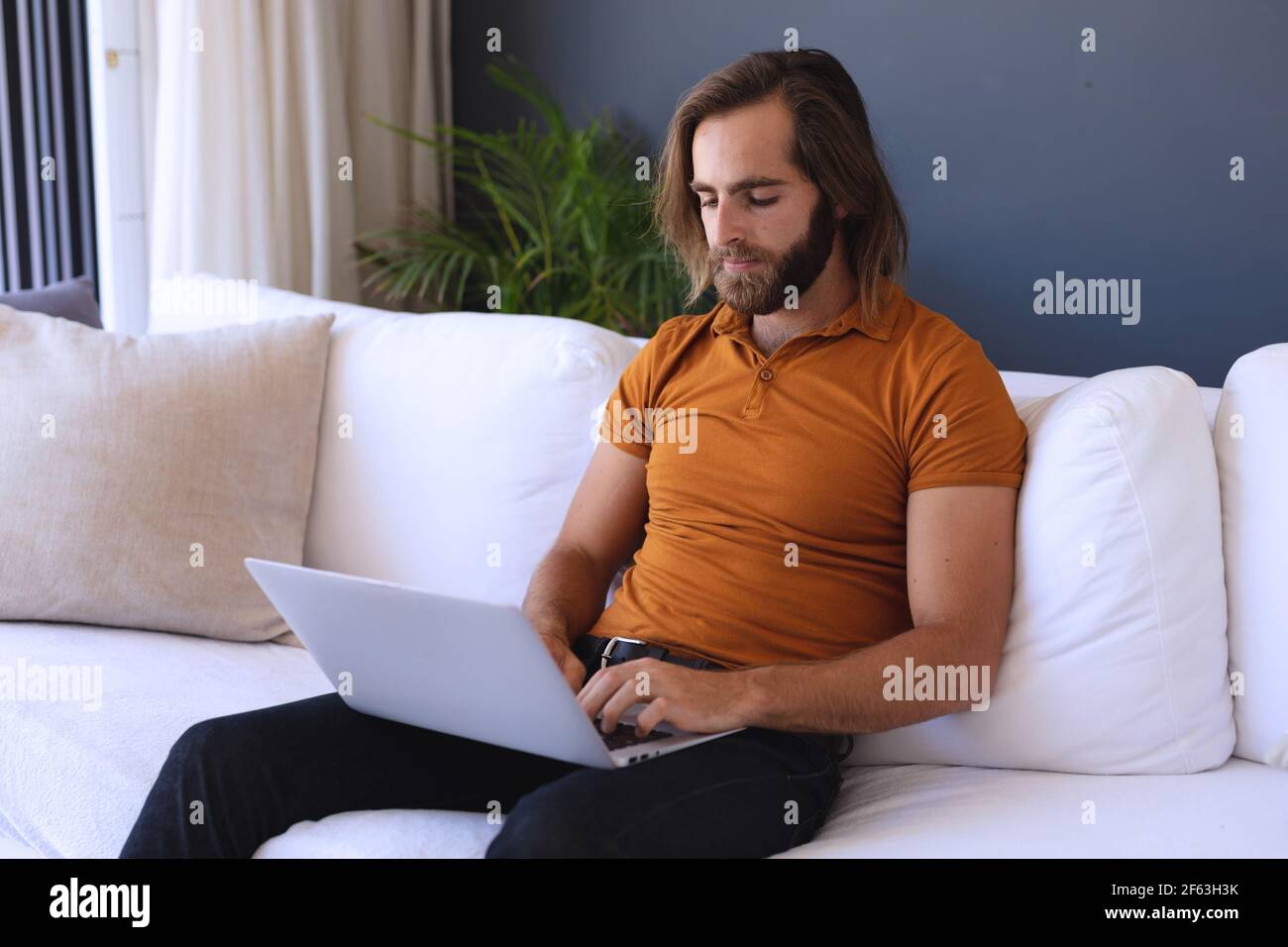 Caucasian man sitting on sofa using laptop Stock Photo