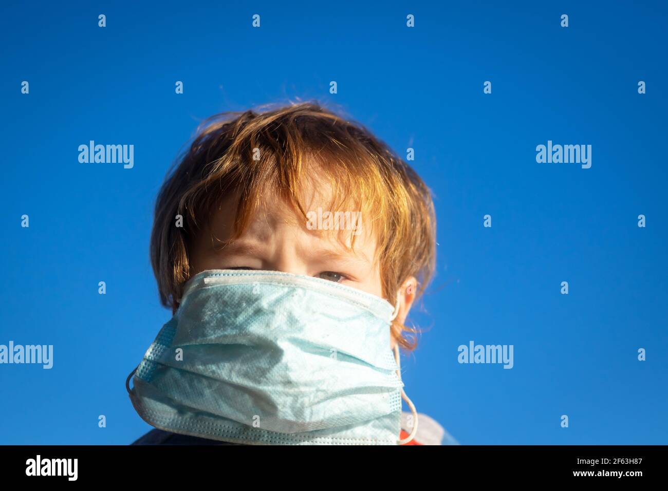 Toddler wearing a face mask, which is too big Stock Photo
