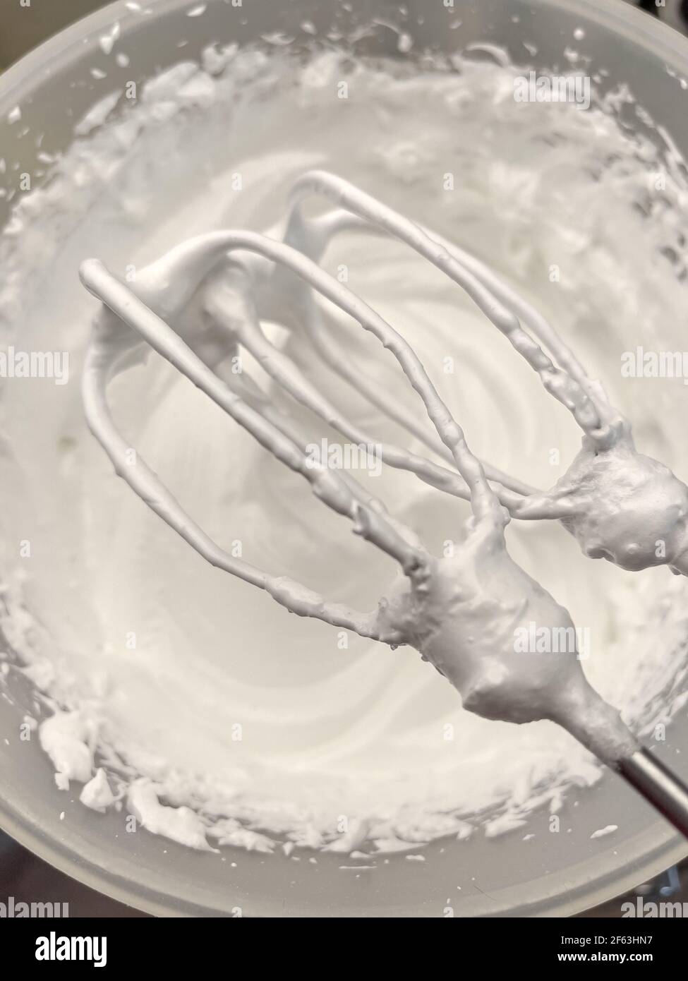 Beaten egg white. Whipped cream white in bowl and mixer, top view Stock