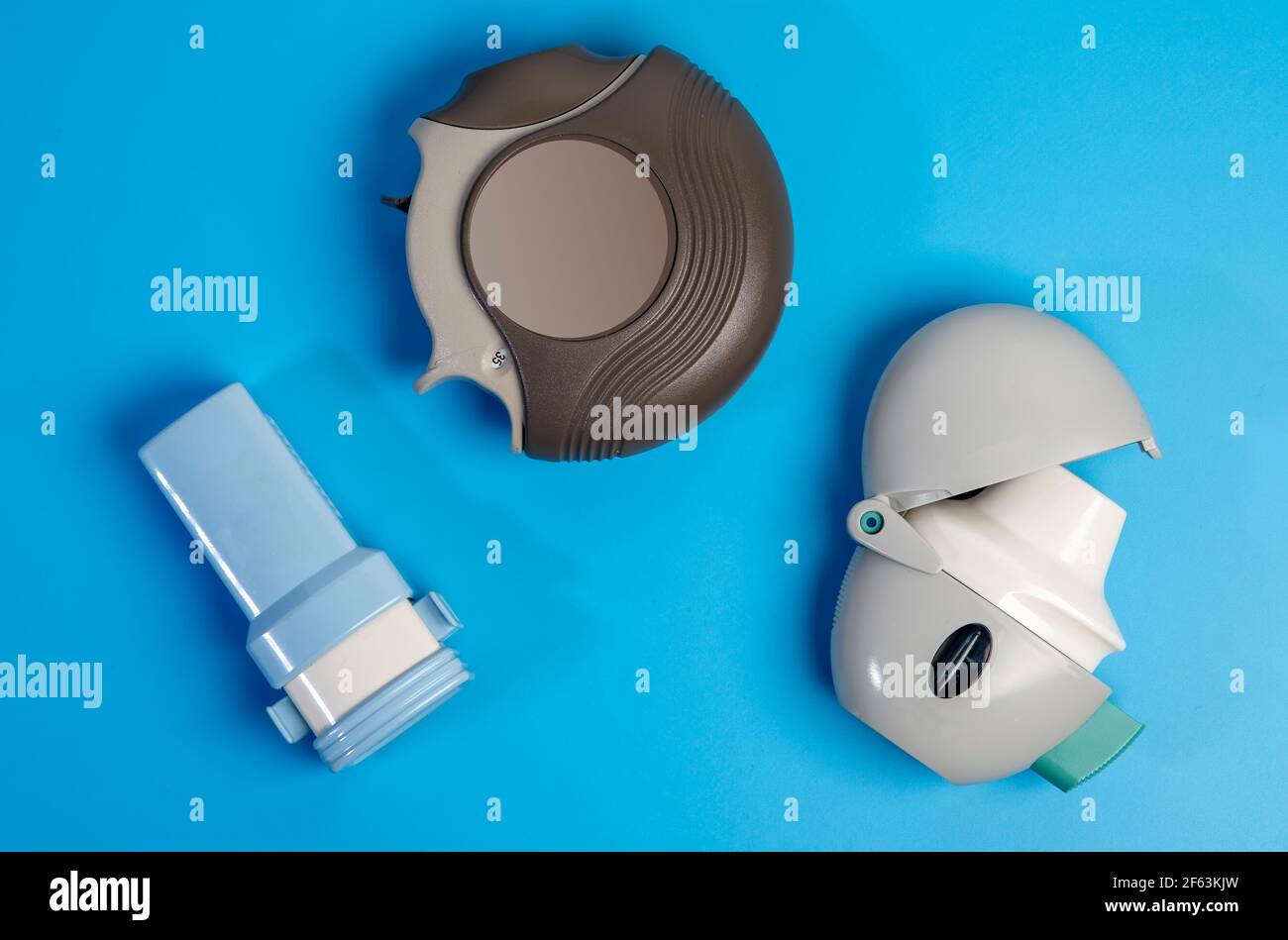 Different types of COPD or Asthma medication instruments ,discus and handihaler and a capsule inhaler.On blue background. Stock Photo