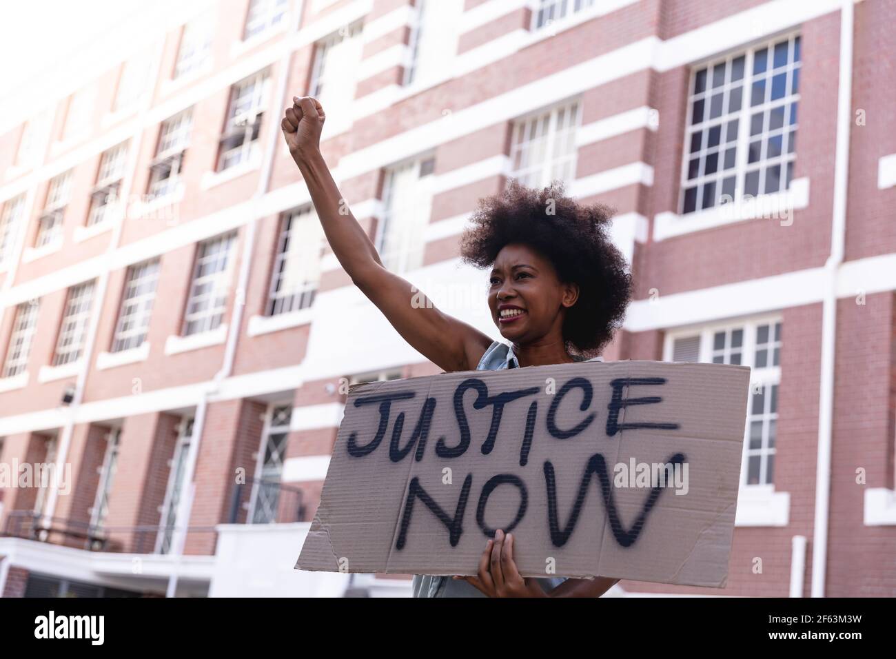 African american female protester on march holding a homemade protest sign raising fist and smiling Stock Photo