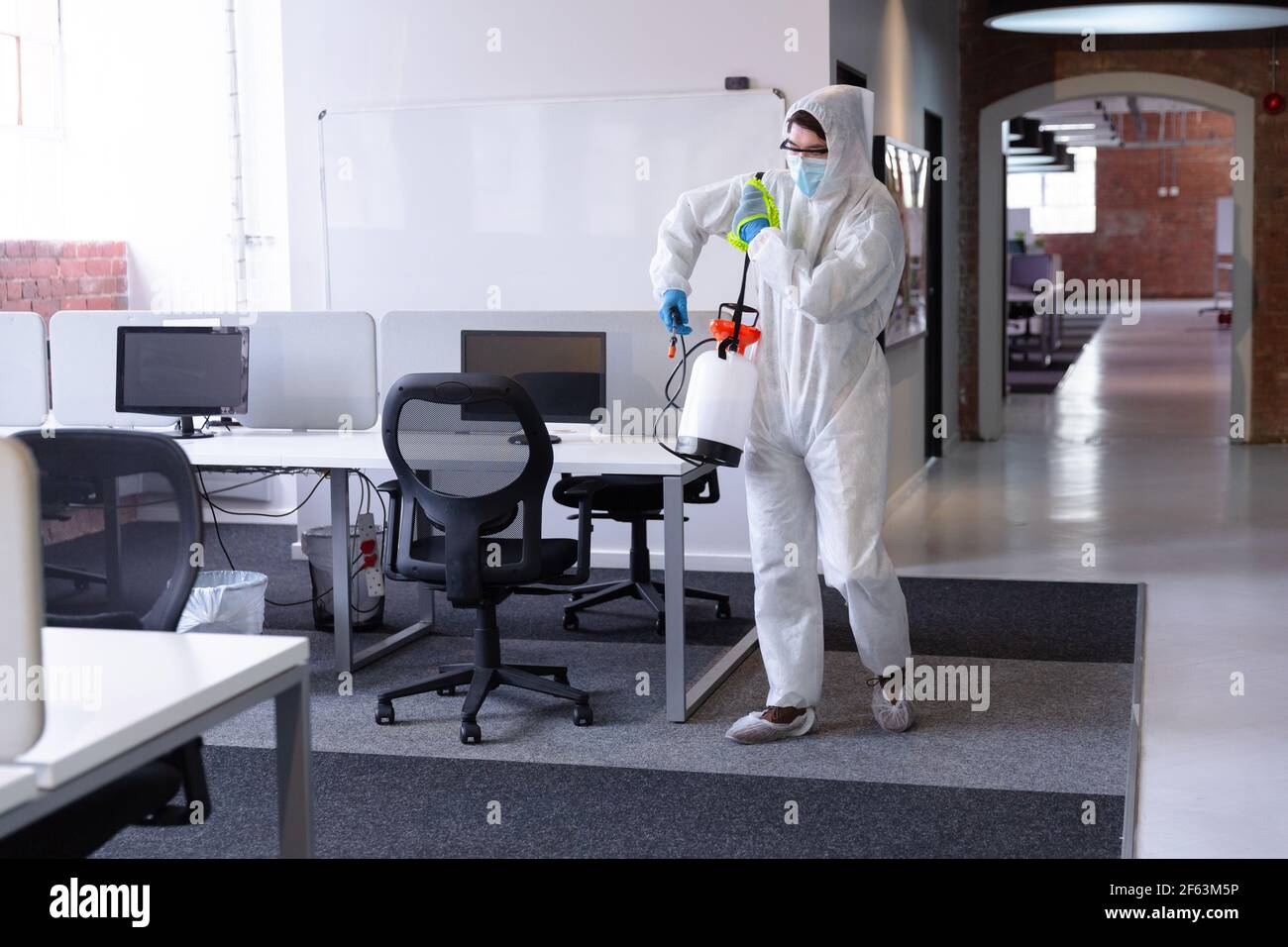 Cleaner wearing hygiene overalls, gloves and face mask carrying ...