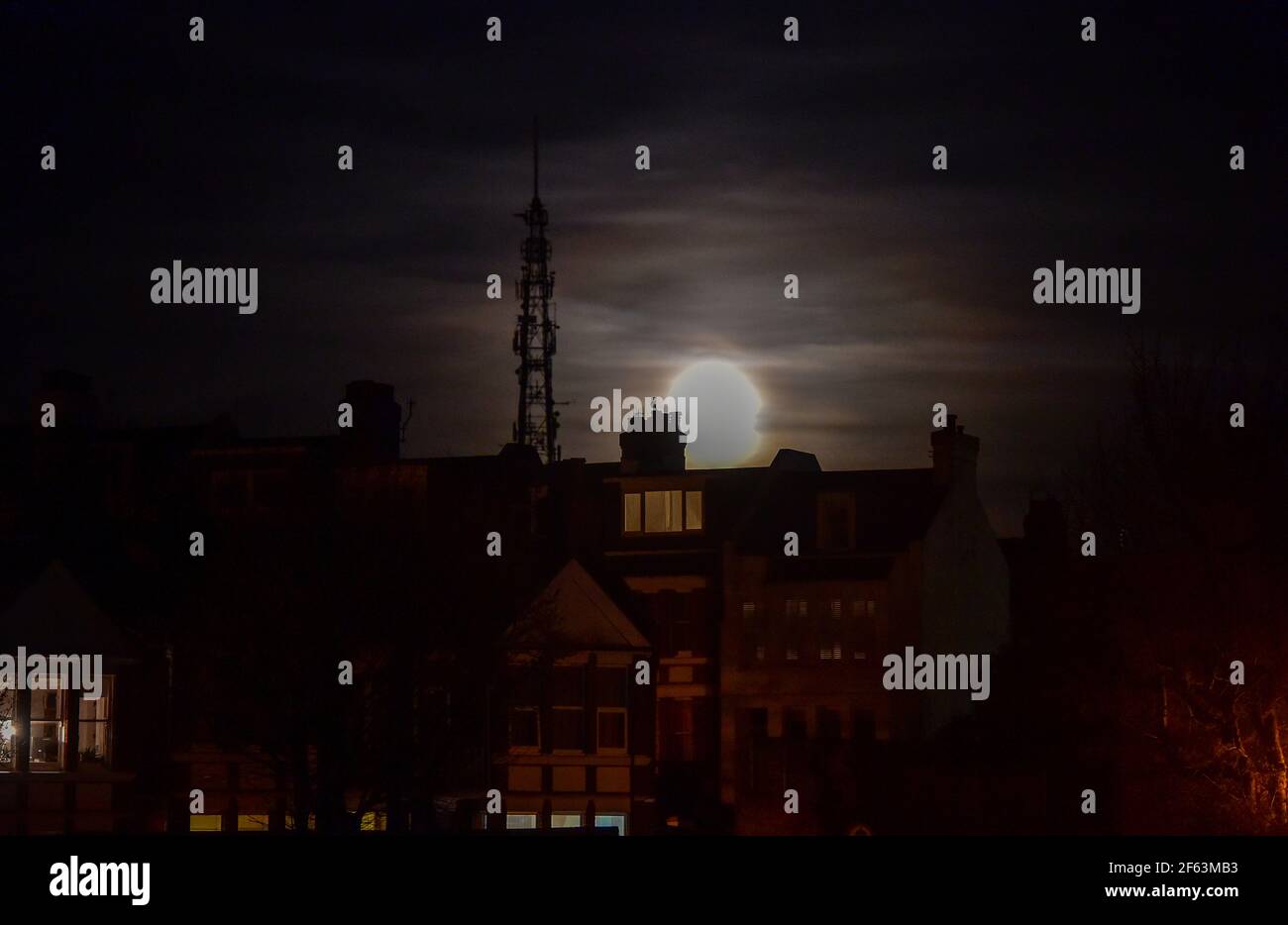 Brighton UK 29th March 2021 - The Worm Moon rises above houses in the Queens Park area of Brighton this evening . This will be the year's first supermoon, meaning the moon is slightly closer to Earth and therefore appears bigger and brighter in the sky. : Credit Simon Dack / Alamy Live News Stock Photo