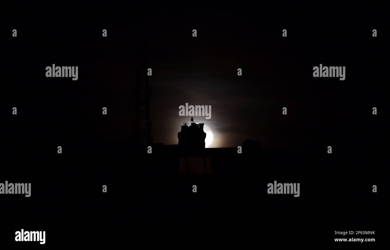 Brighton UK 29th March 2021 - The Worm Moon rises above houses in the Queens Park area of Brighton this evening . This will be the year's first supermoon, meaning the moon is slightly closer to Earth and therefore appears bigger and brighter in the sky. : Credit Simon Dack / Alamy Live News Stock Photo