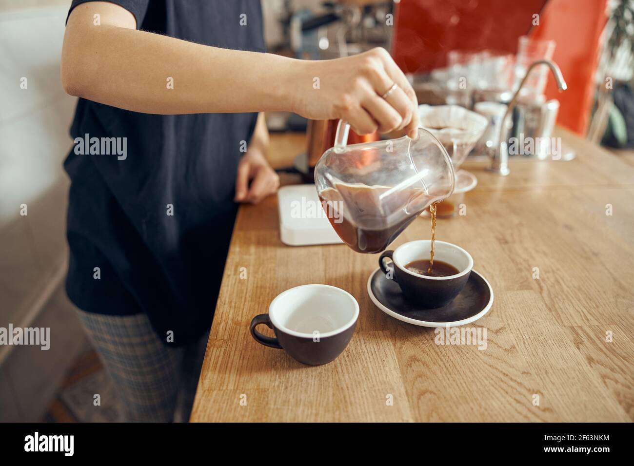 Professional barista photo of barista at counter in cafe pouring filter