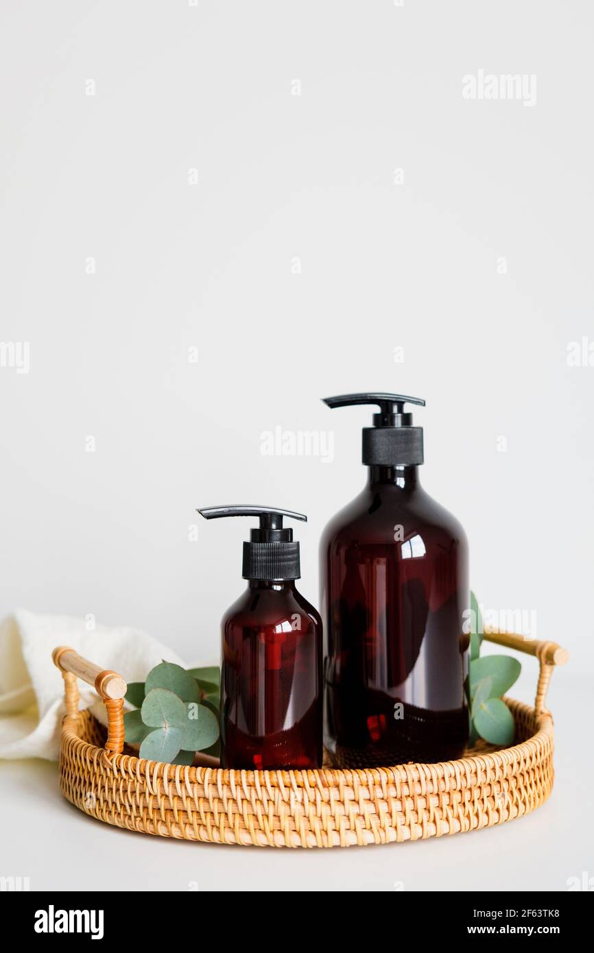 Rattan tray with amber glass bottles of shampoo. Bath cosmetics set, SPA natural organic beauty products. Stock Photo