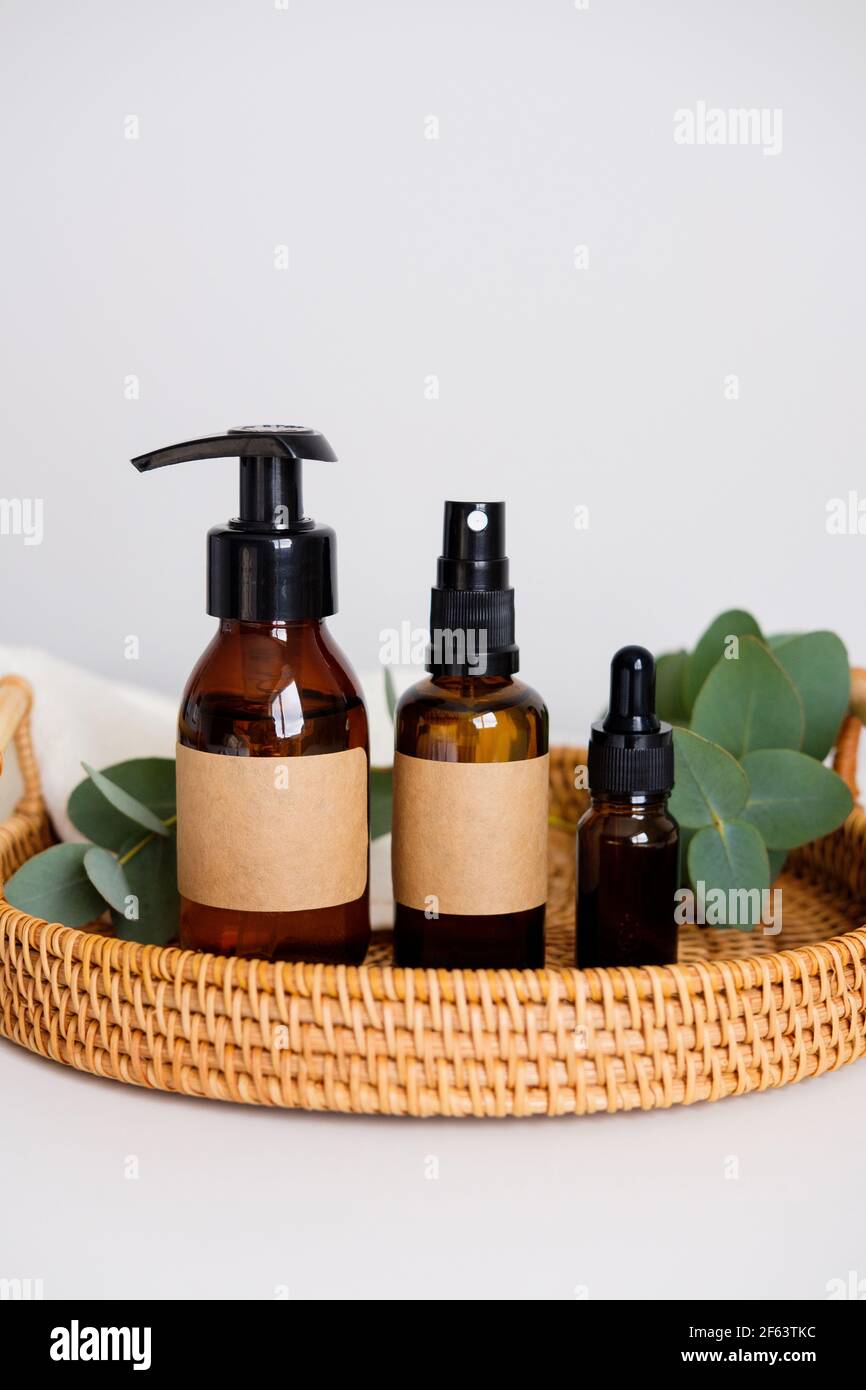 Set of natural organic SPA beauty products in rattan tray with eucalyptus and towel. Amber glass spray bottle, pump, dropper bottles. Stock Photo