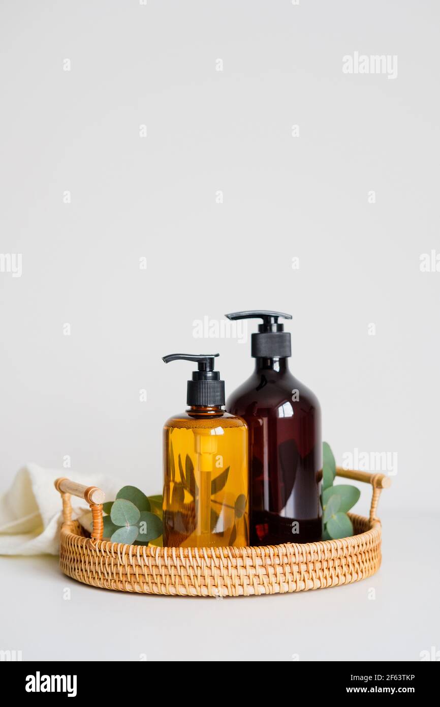 Liquid soap dispenser bottle with eucalyptus and towel in rattan tray. SPA natural organic beauty products set. Stock Photo
