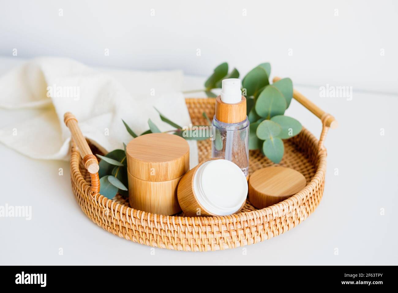 Natural cosmetics set in eco-friendly packaging in rattan tray with eucalyptus and towel. SPA, bath beauty products. Stock Photo