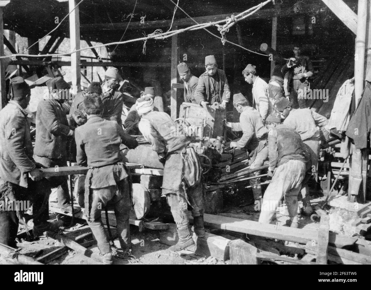 American Red Cross warehouse, Constantinople. Turkish workmen in Red Cross warehouse. Moving a steam winch is one of the American Red Cross warehouses in Constantinople without the help of another steam winch required the services of twenty Turkish laborers. The Red Cross maintains a whole string of warehouses in the Turkish capital in which are stocked food, clothing and medicines for the refugees from Russia who are now being washed through the greatest city of the near east, 1920 Stock Photo
