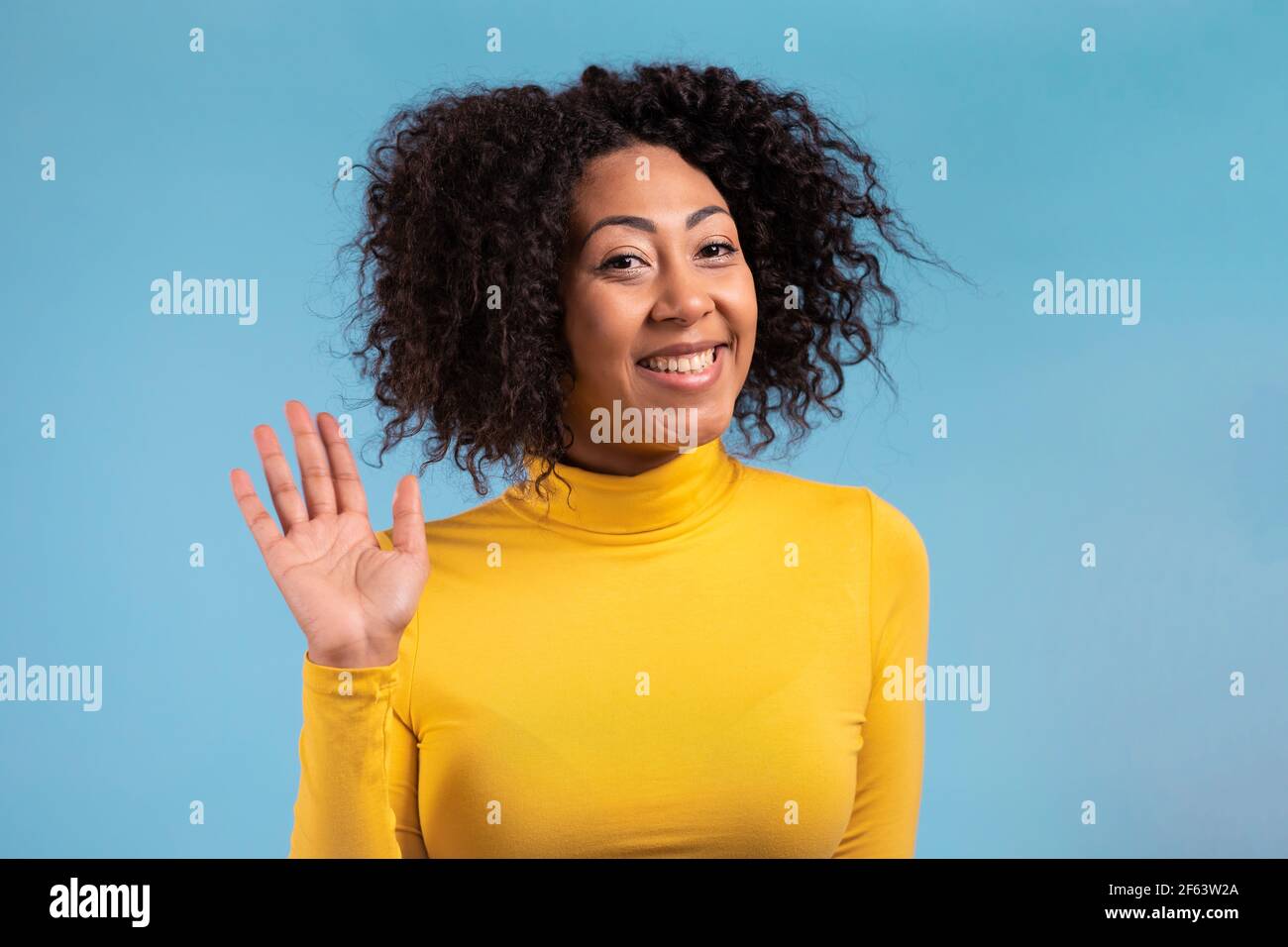 African friendly woman waving hand - hello. Greeting, say Hi to camera.  Beautiful young girl on blue studio background. 4k Stock Photo - Alamy