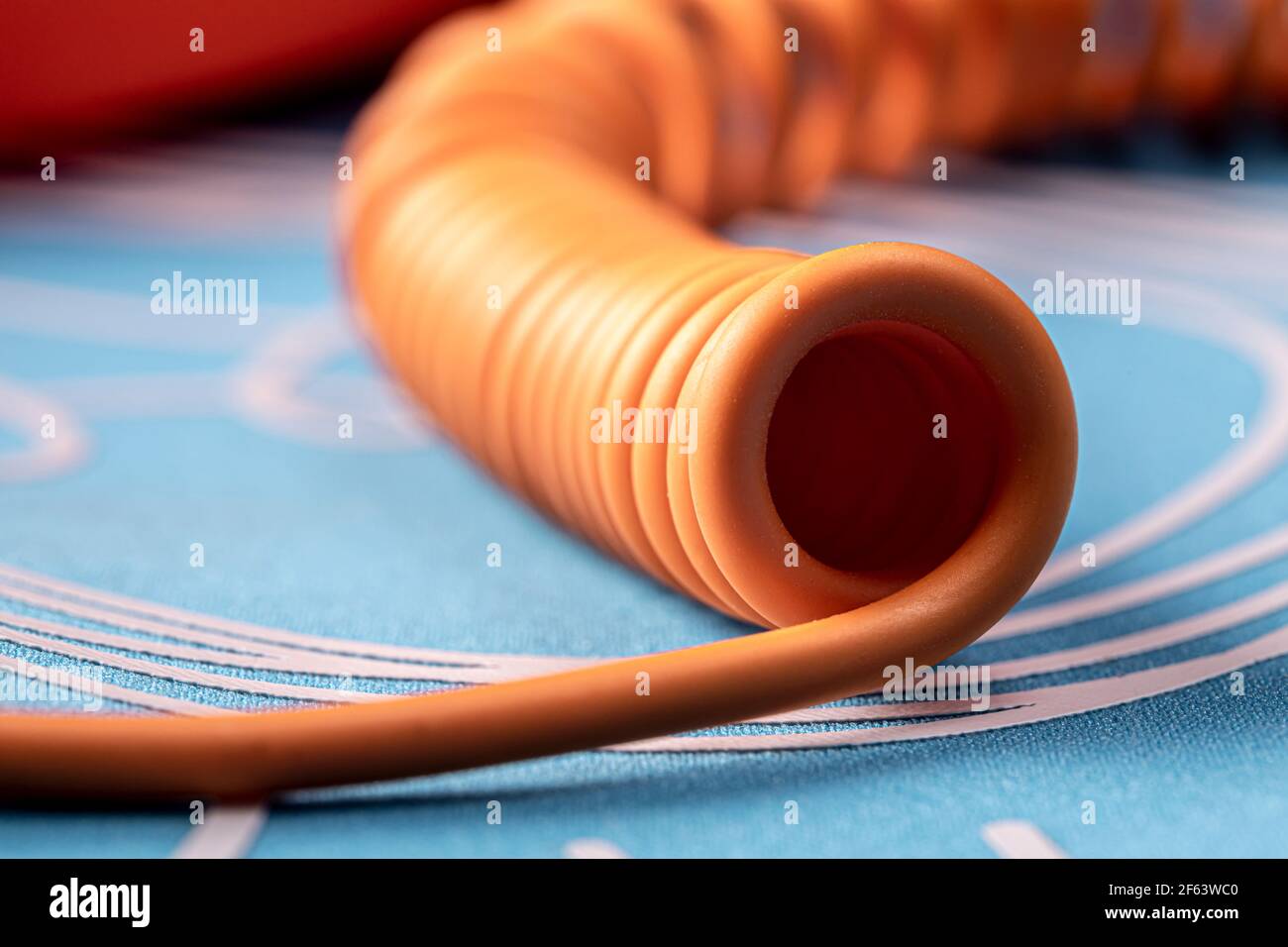 Twisted orange telephone cord on a blue background. Closeup photo with