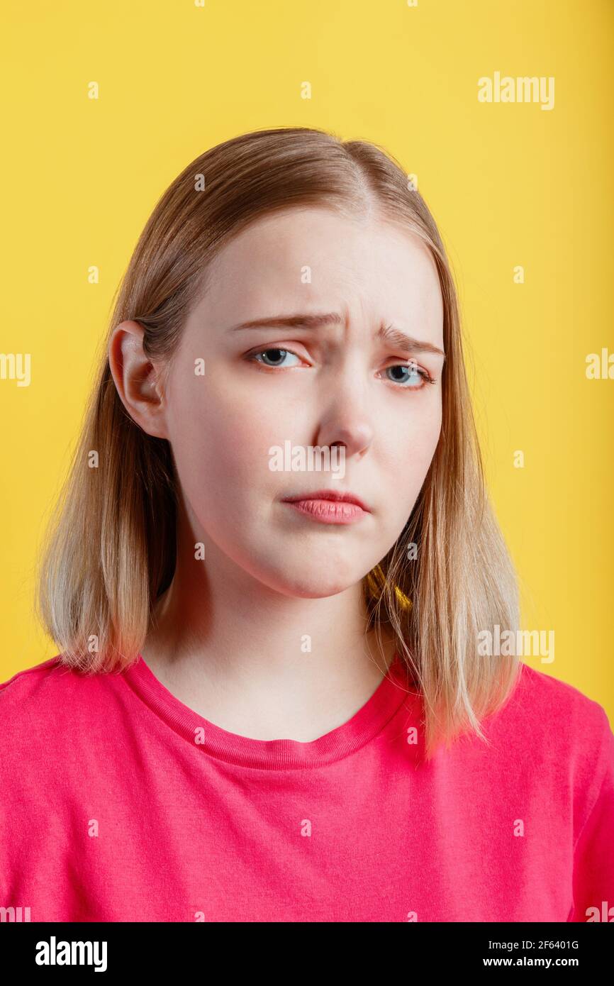 Young woman is upset. Closeup Emotional portrait of teenager girl with grimace of crybaby displeasure sad tired face. Sorry sad lady portrait isolated Stock Photo