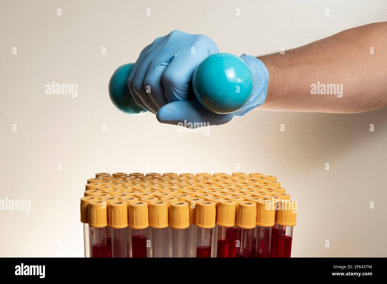 hand with protective nitrile glove holding weight for physical activity with blood collection