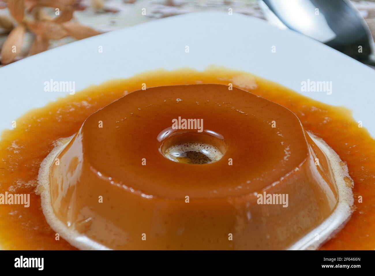 Closeup on the central circle of dulce de leche pudding with caramel sauce, selective focus. A traditional Brazilian sweet. Stock Photo