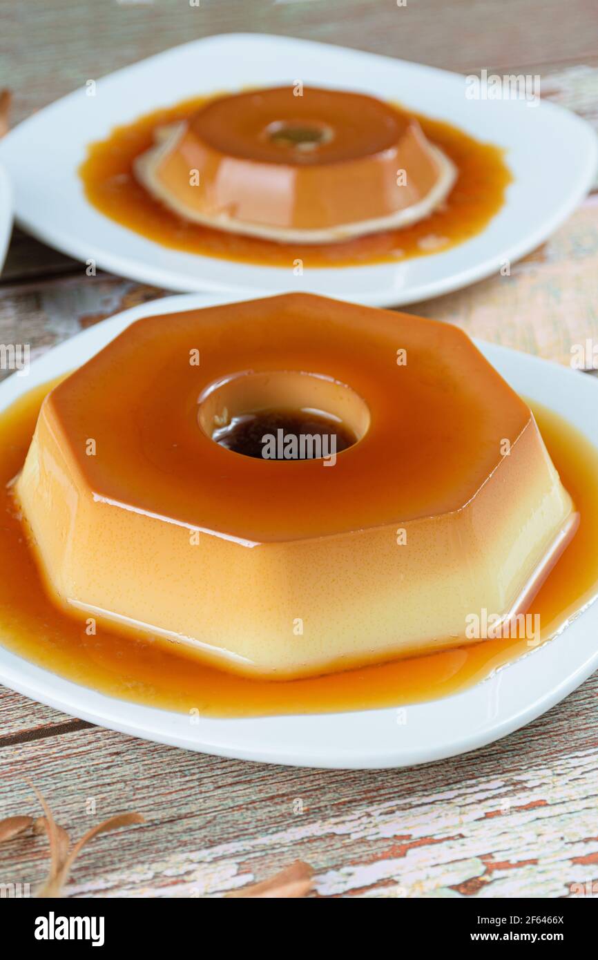 Condensed milk pudding with caramel syrup. Dulce de leche pudding in the background. Brazilian traditional sweets (vertical photo). Stock Photo