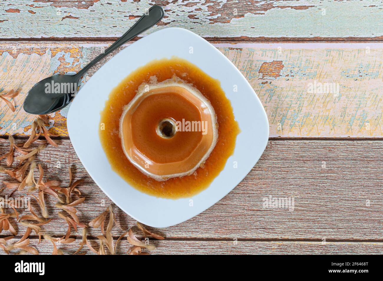 Dulce de leche pudding with caramel syrup, alongside flying seeds (Triplaris americana). A traditional Brazilian sweet (top view). Stock Photo