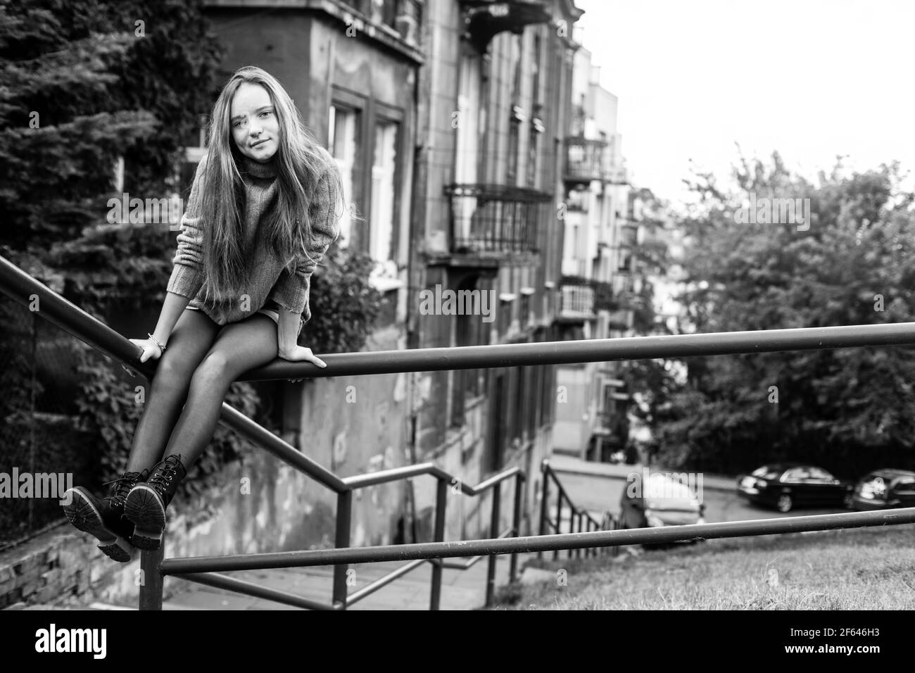 Long-haired girl sitting on the parapet in the old town. Black and white photo. Stock Photo
