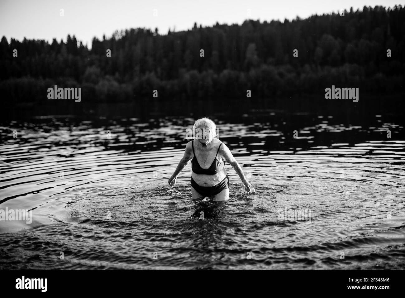 An old woman swimming in the summer river. Black and white photo. Stock Photo