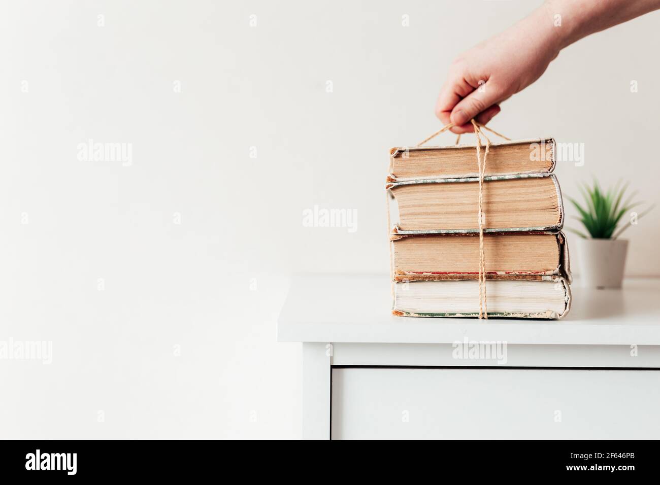 Hand holding a stack of old books in the library, concept of learning, study and education, concept of science, wisdom and knowledge. High quality pho Stock Photo