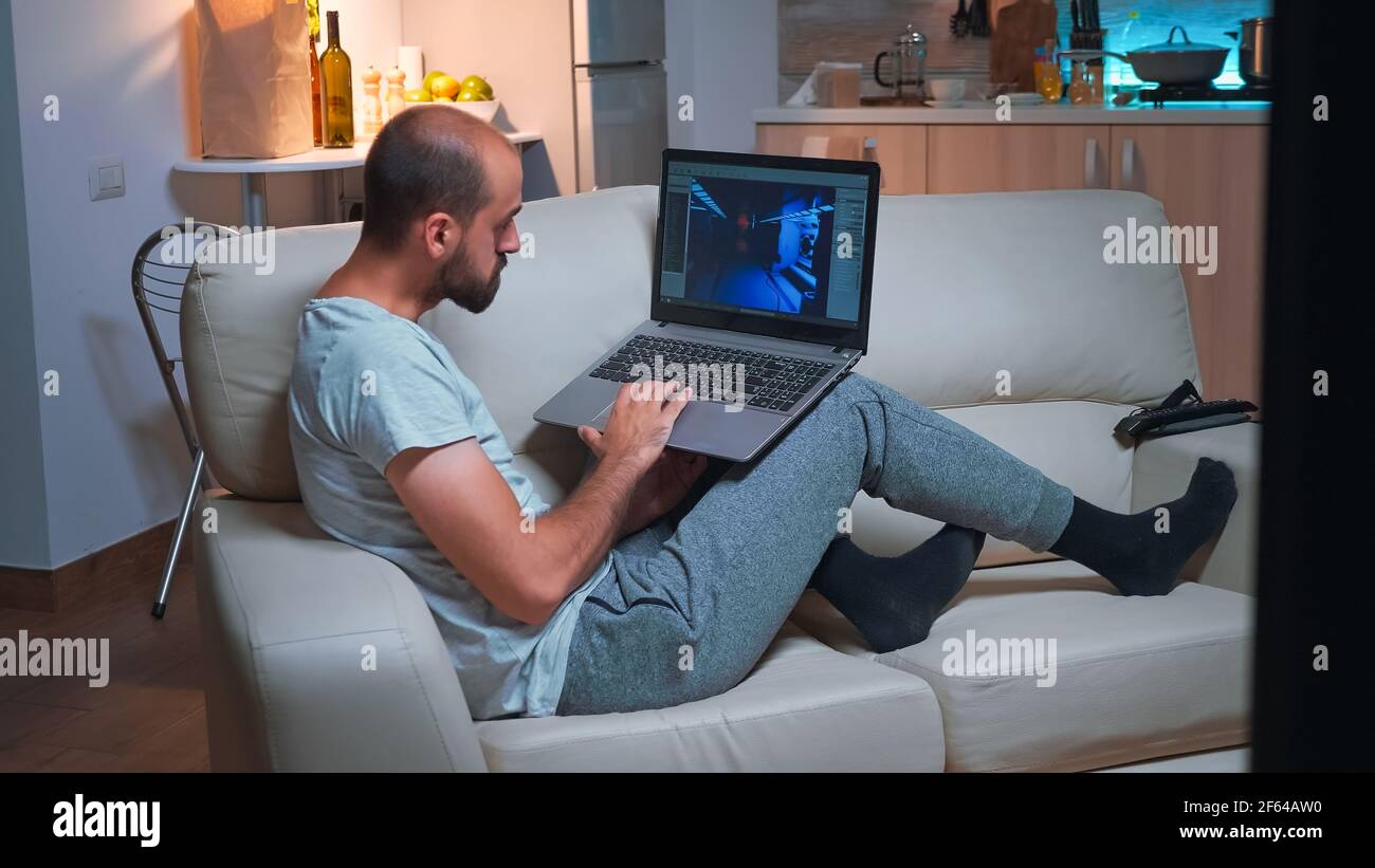 Professional game developer working on gameplay and game level late at night from the confort of his home. Professional creative man in the evening developing startup technology Stock Photo
