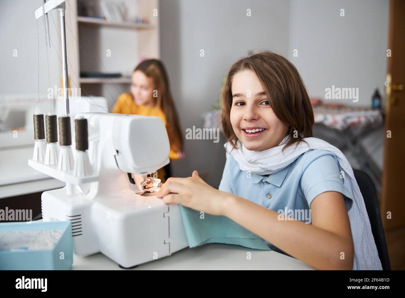 Cheerful girl using sewing machine in tailor studio Stock Photo