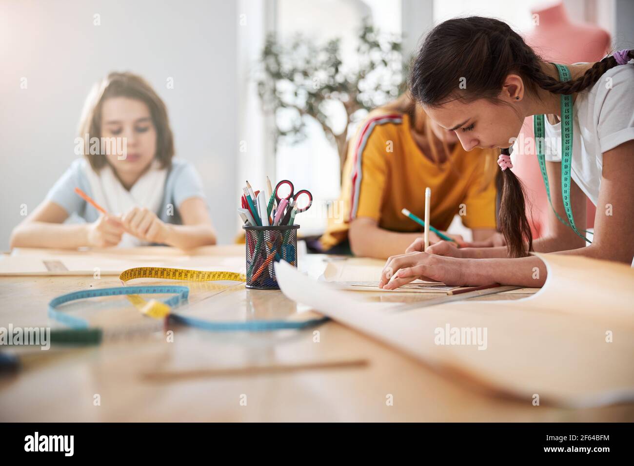 Cute female kids making sewing patterns in workshop Stock Photo - Alamy