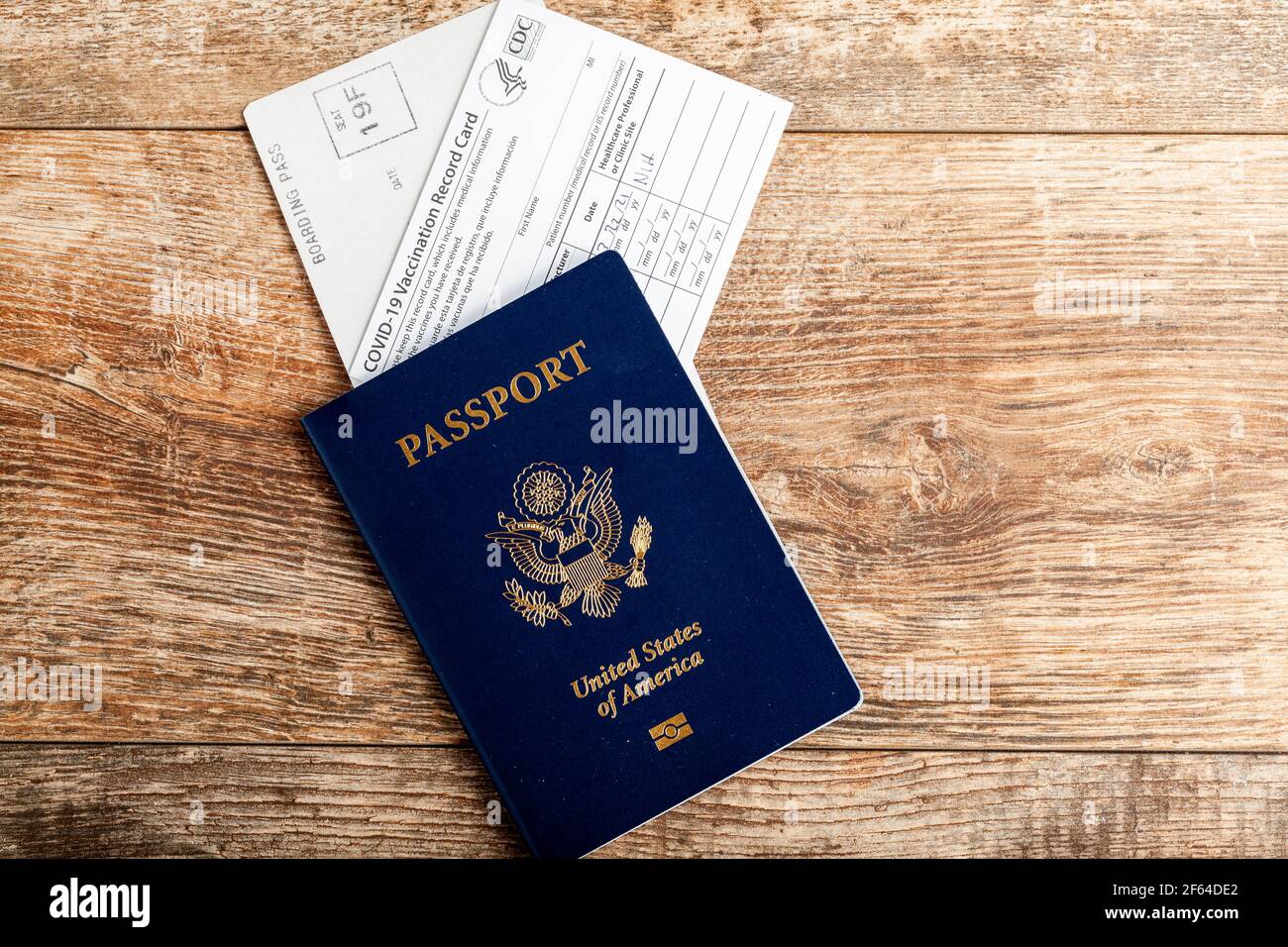 Clarksburg, MD, USA 03-30-2021: Flat lay top view image of a US passport, a boarding pass and a HHS COVID-19 vaccination record card on wooden backgro Stock Photo