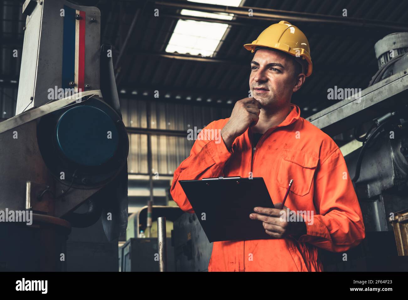 Skillful factory worker working with clipboard to do job procedure