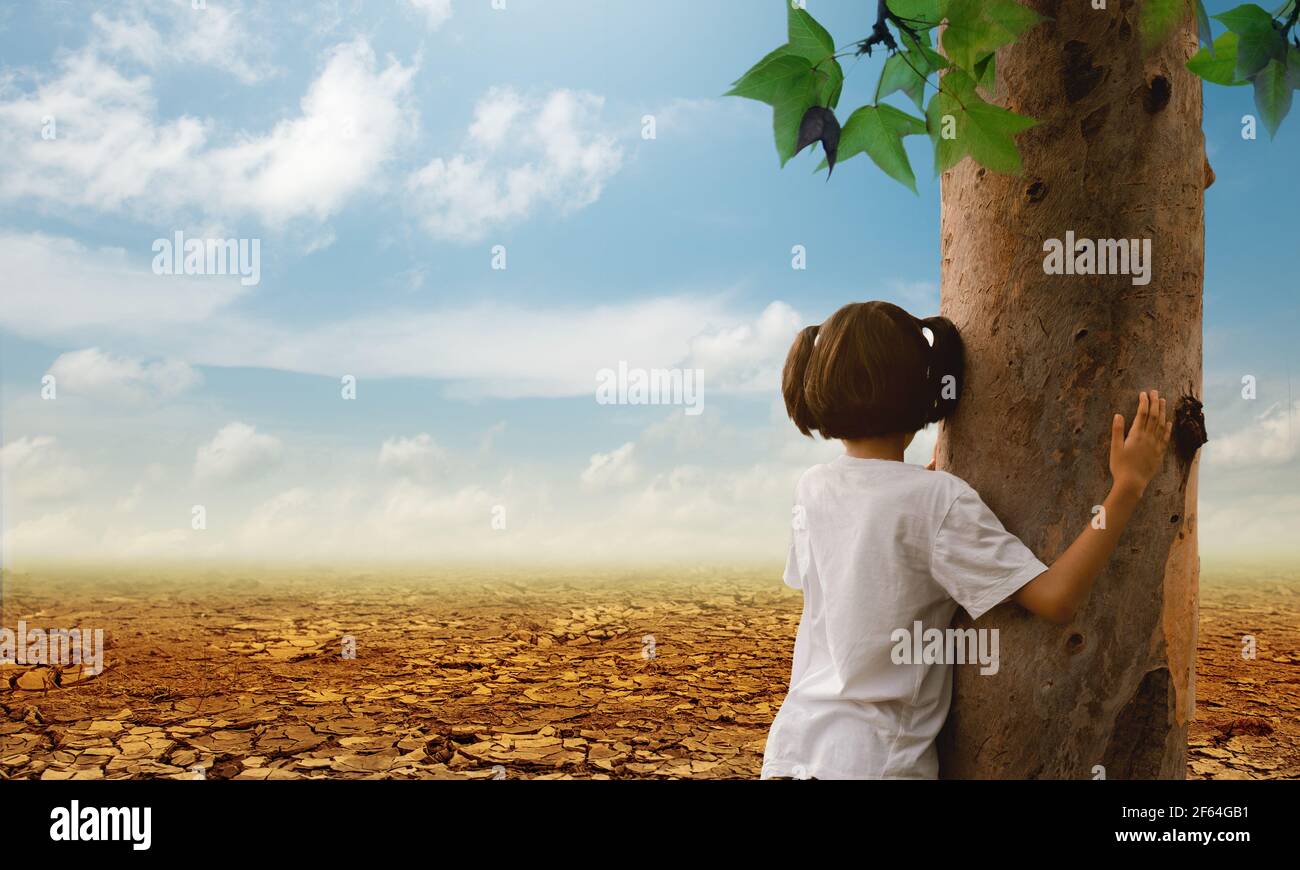 Girl hugging a tree on the cracked earth background. Global warming. Stock Photo