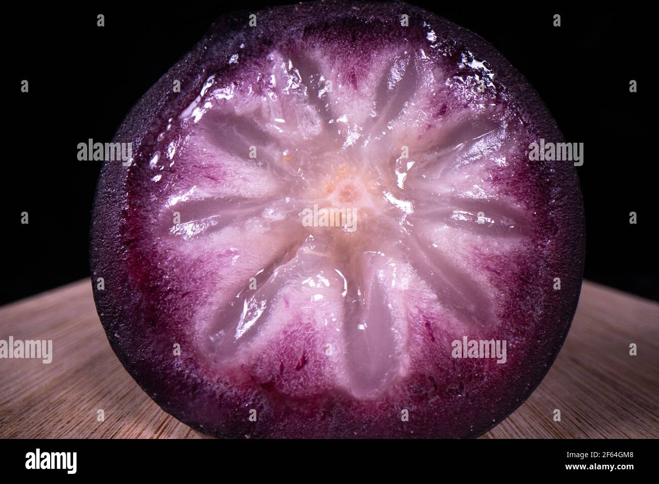 A ripe star apple showing the colourful fruit cut in half, a popular